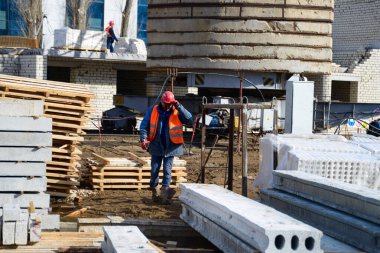 Ev yapımı. Bir işçi inşaat alanında yürür. Binaların inşaatı için beton levha şantiyede..