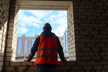 Ev yapımı. Tamamlanmamış bir evin penceresinden çok katlı yeni binaların ve mavi gökyüzünün manzarası. İnşaat sektöründe kriz.