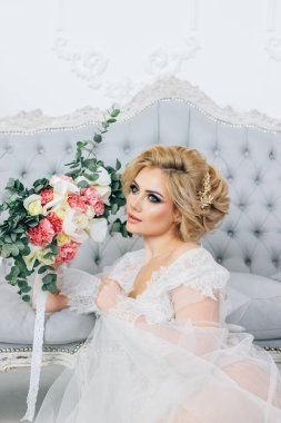 güzel sarışın bir sabahlık saç ve makyaj ile içinde bir düğün buket tutuyor