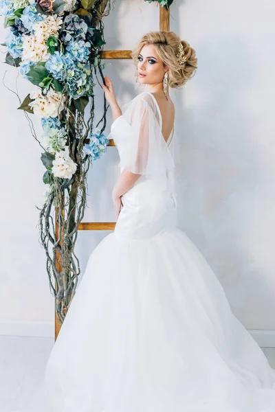A menyasszony áll egy fehér háttér, virágok a kezében — Stock Fotó