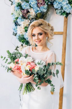 bir arka plan duvar ve çiçek bir buket ile bir gelinlik güzel bir gülümsemeyle kız eller