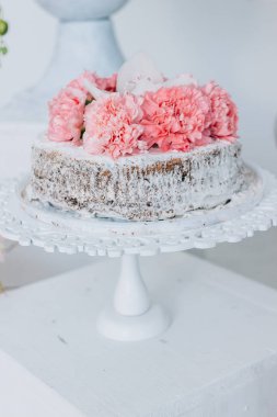 Pandispanya düğün beyaz bir kaide üzerinde taze çiçekler ile dekore edilmiş