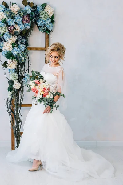Egy-egy csokor, az esküvői ruha gyönyörű lány kezét a háttérben a falra — Stock Fotó