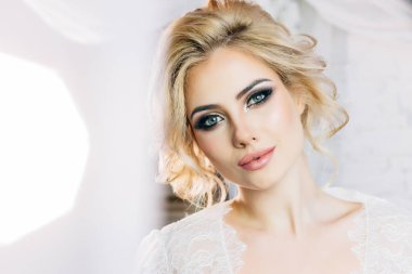 Anlamlı gözleri ve beyaz bir sabahlık tatlı bir gülümseme ile güzel model