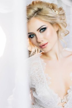 Anlamlı gözleri ve tatlı bir gülümsemeyle styling saç beyaz bir sabahlık tarafından yapılan güzel model