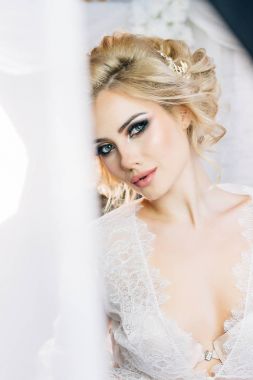 Anlamlı gözleri ve tatlı bir gülümsemeyle styling saç beyaz bir sabahlık tarafından yapılan güzel model