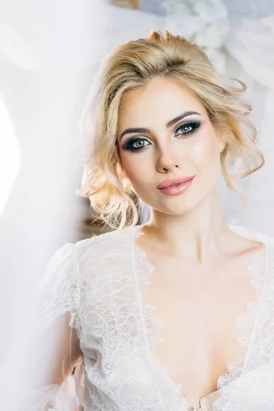 Beautiful model with expressive eyes and a sweet smile in a white negligee