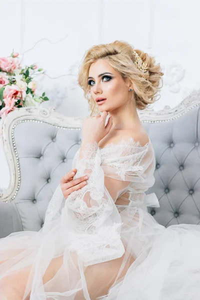 Kanepede oturan güzel sarışın kız bir düğün buket tutan bir beyaz sabahlık giymiş bir hava öpücük çok renkli arka planda gönderme