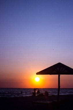 yaz günbatımı güneş, plaj mantar siluetleri, dinlenme insan siluetleri. Günbatımı