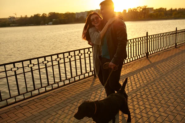 Happy young couple walking with dog on street. — Stock Photo, Image