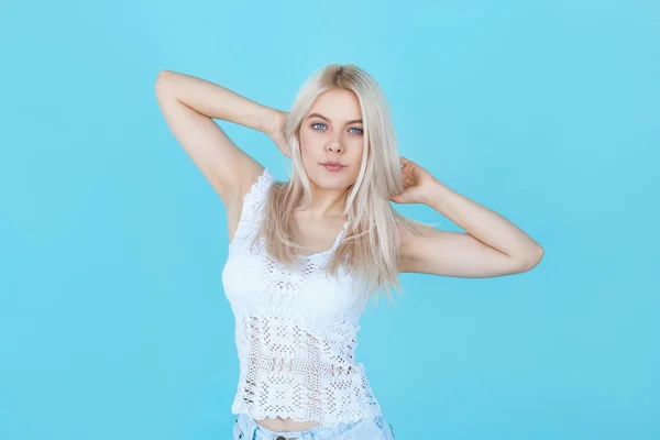 Joven rubia hembra en ropa blanca posando sobre fondo azul — Foto de Stock
