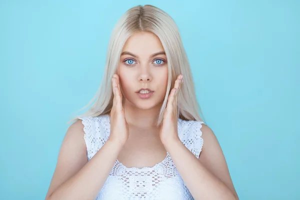 Wide eyed young teenage girl in shock over blue background