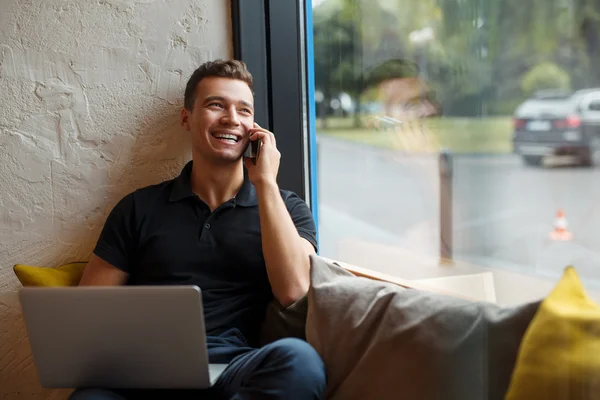Uśmiechnięty mężczyzna za pomocą laptopa i dzwoniąc — Zdjęcie stockowe