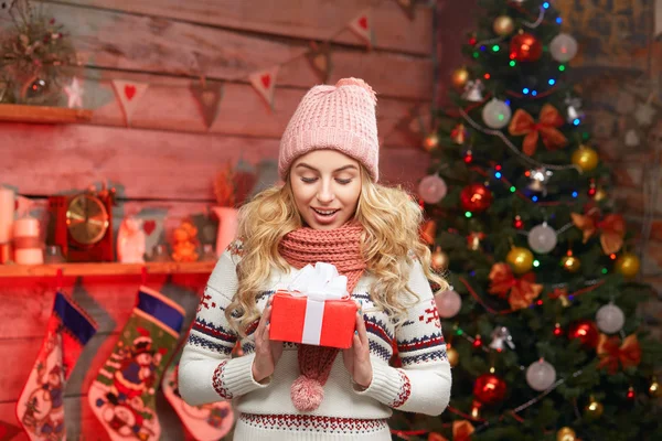 Mulher na moda camisola com caixa de presente sobre sua árvore de natal — Fotografia de Stock