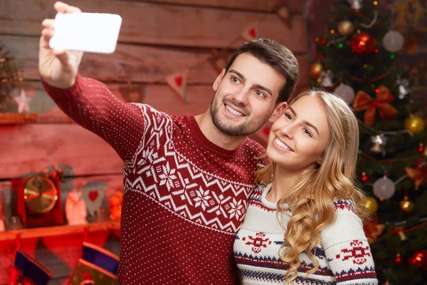 Paar macht Selfie auf Smartphone vor Weihnachtsbaum-Hintergrund — Stockfoto