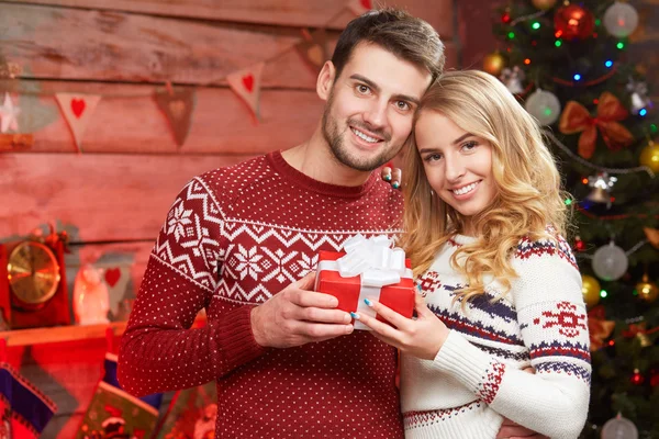 Glücklicher junger Mann hält Weihnachtsgeschenk mit seiner Freundin — Stockfoto