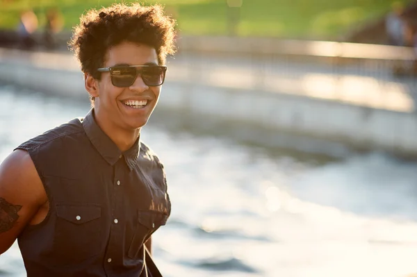 Bonito jovem faculdade menino sorrindo no fundo azul ao ar livre — Fotografia de Stock