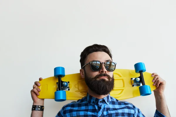 Bonito skatista, segurando um skate atrás da cabeça . — Fotografia de Stock