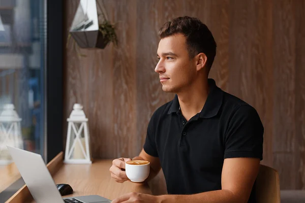 Młody przystojny mężczyzna siedząc w kawiarni, przy filiżance kawy — Zdjęcie stockowe