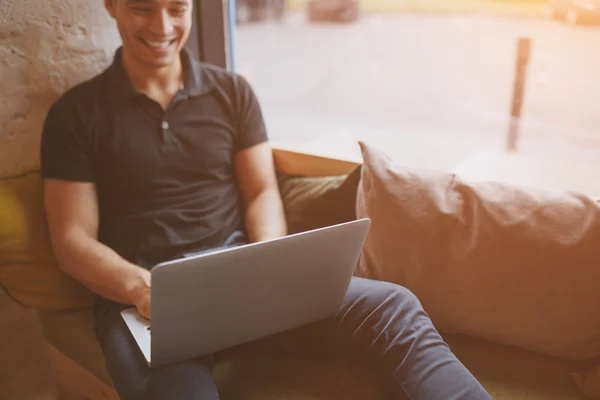 Młody mężczyzna pracujący na laptopie siedząc w wygodne kanapy — Zdjęcie stockowe