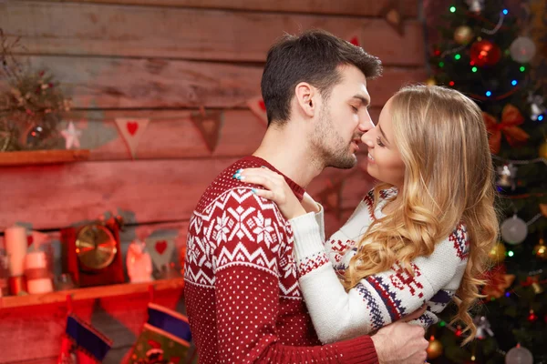 Feliz jovem casal apaixonado por árvore de natal beijando . — Fotografia de Stock