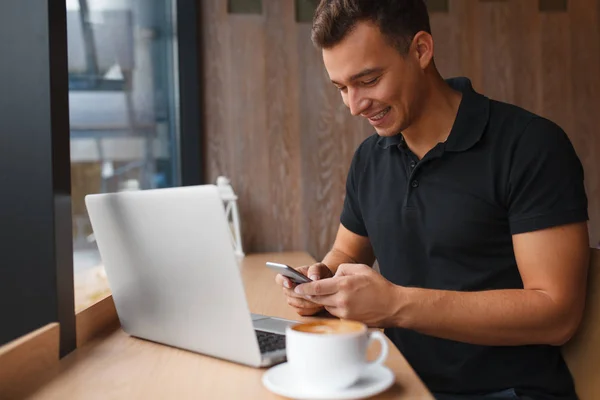 Człowiek siedzi w kawiarni z inteligentny telefon — Zdjęcie stockowe