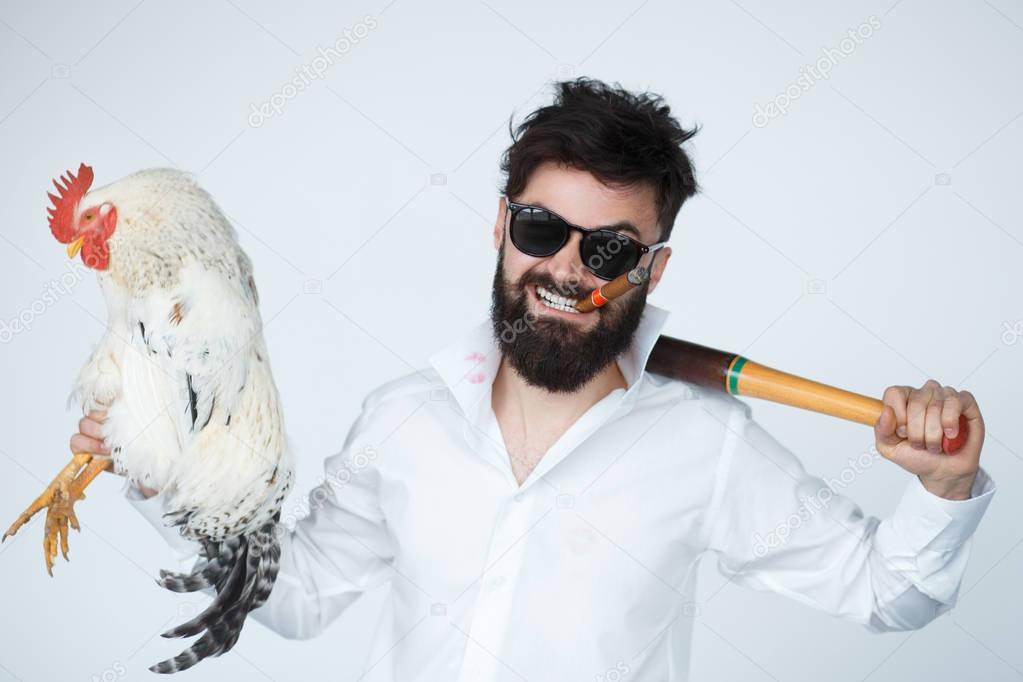 Crazy guy in rage holding a cock and baseball bat.