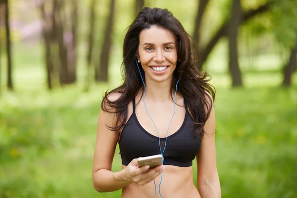 Smiling woman runner listening to music on smart phone