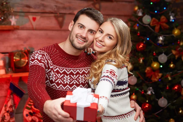 Young man and woman holding a wrapped gift — Stock Photo, Image