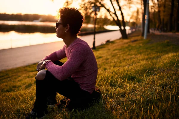 Человек, сидящий на траве на закате — стоковое фото