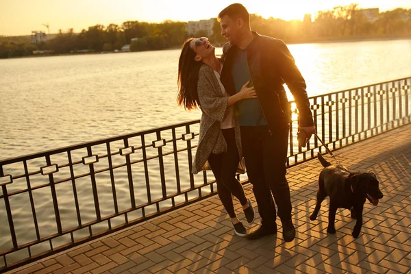 Paar spelen met de hond in park bij zonsondergang — Stockfoto