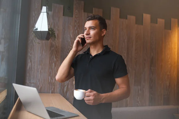 Szczęśliwy młody człowiek za pomocą laptopa i telefonu komórkowego na kanapie — Zdjęcie stockowe