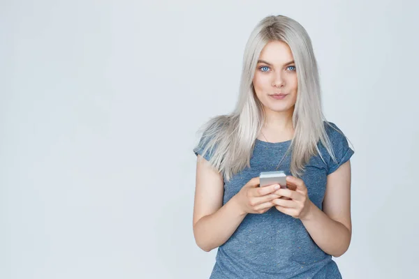 Chica feliz en camiseta mensajes de texto en un teléfono inteligente — Foto de Stock