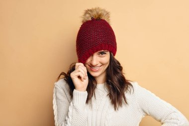 bej renkli arka plan üzerinde örme kazak giyen genç kadın