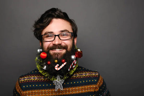 Человек с рождественскими украшениями на сером фоне — стоковое фото