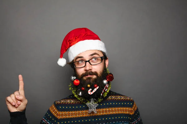 Geeky jovem em Papai Noel chapéu apontando para cima — Fotografia de Stock