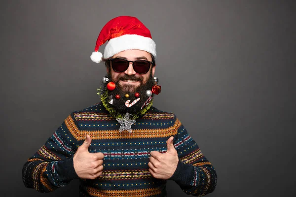 Bearded male in santa hat shows thumbs up.