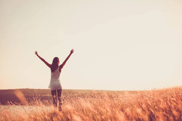 Freie Frau hebt die Arme zum goldenen Sonnenuntergang — Stockfoto