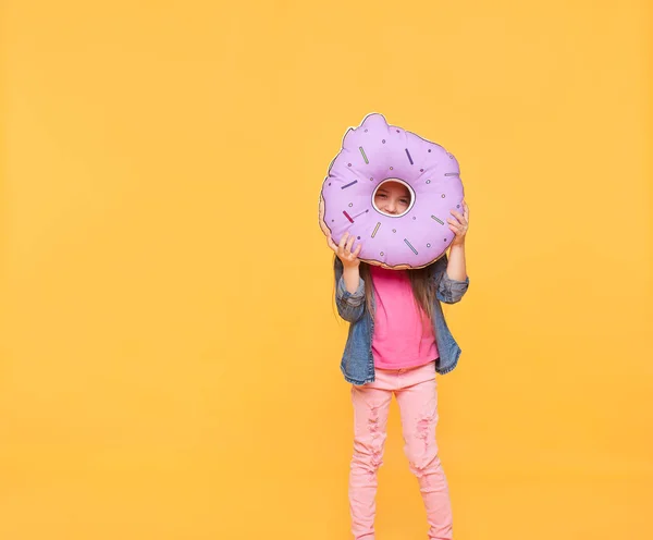 Meisje op zoek door middel van een grote donut — Stockfoto