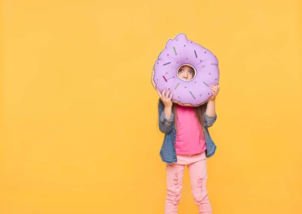 Kleines Mädchen spielt mit großem Spielzeug in Form von Donut — Stockfoto