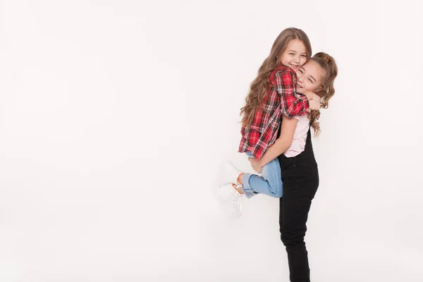 Duas meninas brincando e abraçando no fundo branco — Fotografia de Stock