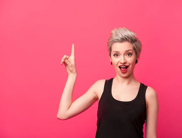 Modelo com cabelo curto loiro apontando para cima em rosa — Fotografia de Stock