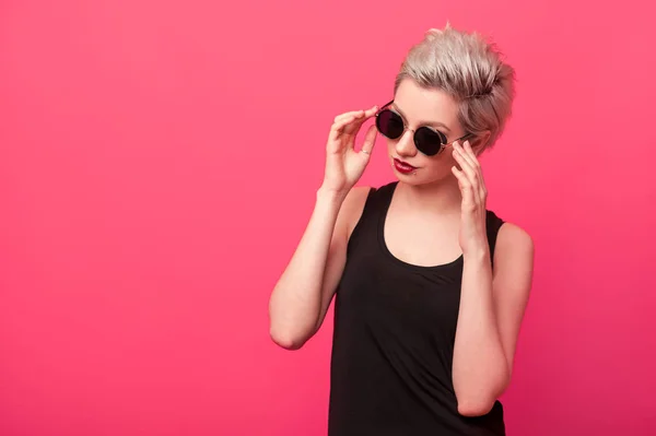 时尚女孩在黑色的衬衫和太阳镜上粉红色背景 — 图库照片