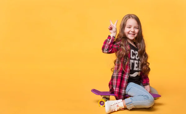 Menina feliz criança rindo enquanto sentado no skate — Fotografia de Stock