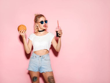 Bir hamburger ve bir bardak soda tutan kadın