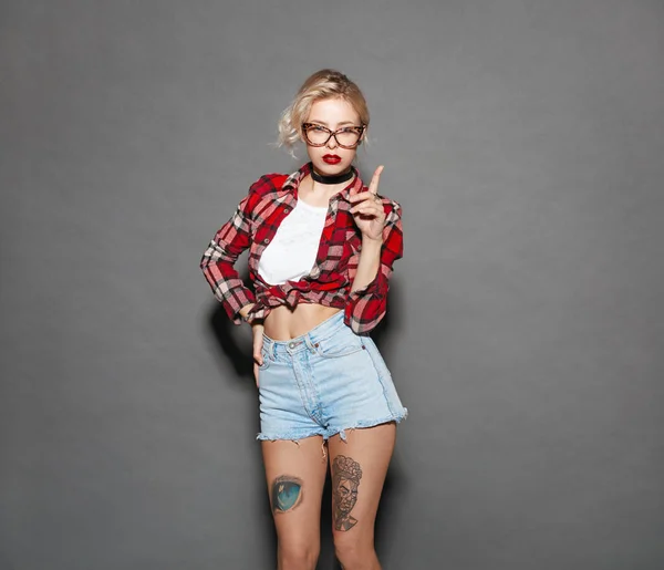 Tattooed girl in checkered shirt and glasses — Stock Photo, Image