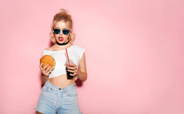 Menina em óculos de sol segurando hambúrguer e cola — Fotografia de Stock