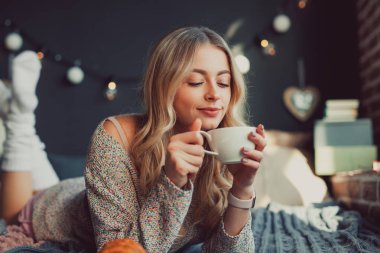 Genç kadın yatakta içecek