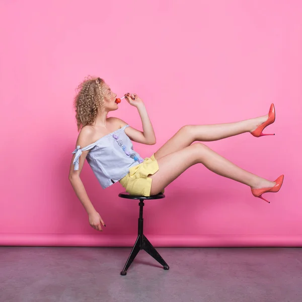 Модная девушка позирует на стуле с поднятыми ногами — стоковое фото