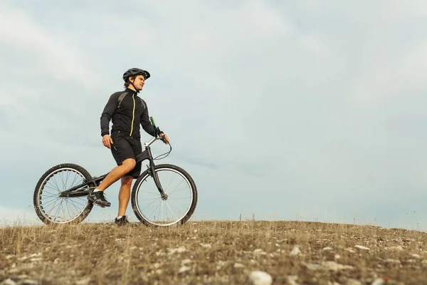 Homme avec vélo de trial debout sur une montagne — Photo